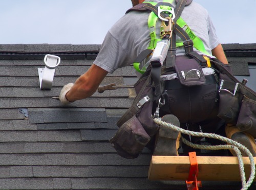 man fixing the shingles on a roof