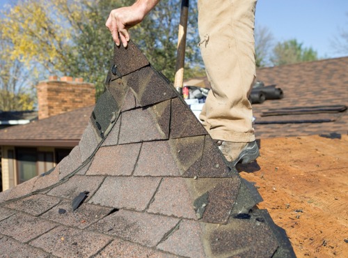 A contractor in the process of tear-off roofing in Champaign IL