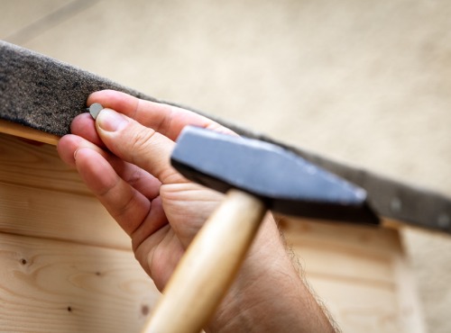 Close Up of Man Hammering Nail into Roofs near Champaign IL