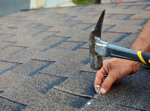 Roofing Companies in Urbana IL nailing shingles onto a roof