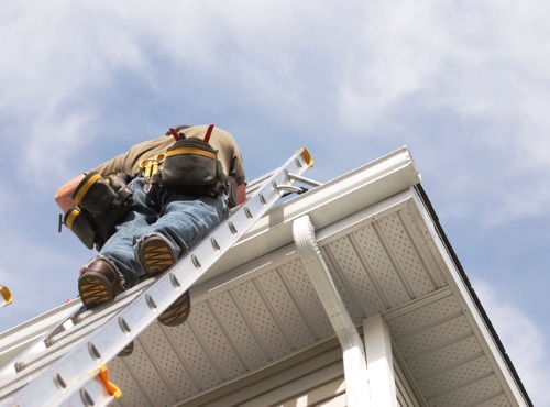 Man Standing On Ladder Inspecting Commercial Roofing in Urbana IL