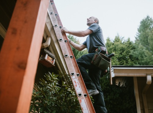 Roofer climbs a ladder to start on a roof replacement in Normal IL