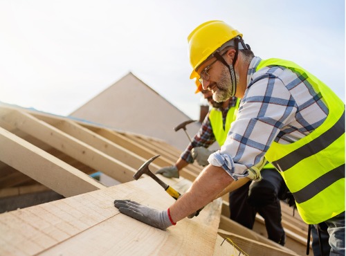 Workers are seen installing a new roof. Ask Popejoy Roofing about commercial roofers in Mahomet IL.