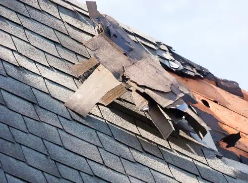 A damaged roof is seen. If you're wondering, "What do shingles falling off my roof mean?" call Popejoy Roofing.