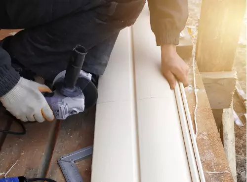 A worker is seen cutting siding. Popejoy Roofing is a siding company.