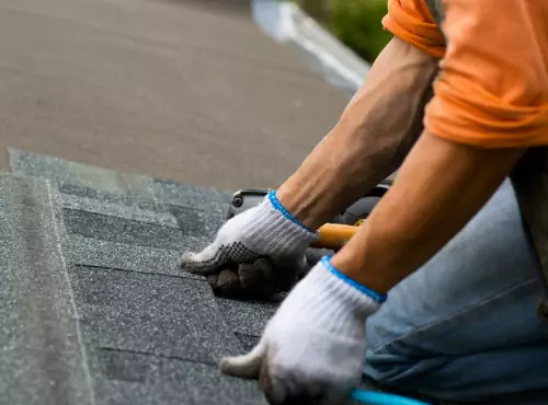 A team member of Popejoy Roofing installs roofing, which is one of the services offered in addition to Composite Siding in Champaign IL