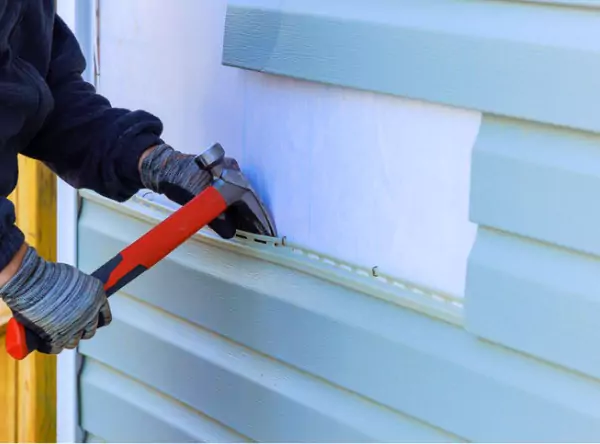 A contractor from Popejoy installing new siding, part of their Roofing & Exterior Services in Central Illinois