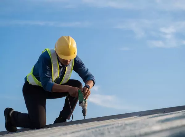 A worker repairing a roof, as a part of Roofing & Exterior Services offered by Popejoy Roofing